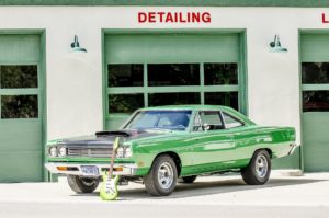 AMSOIL Motor Oil with Zinc for Older Cars 7 Classic green muscle car with a guitar leaning on it in front of detailing shop.