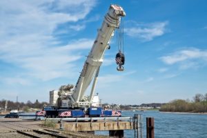 White hydraulic crane near river.