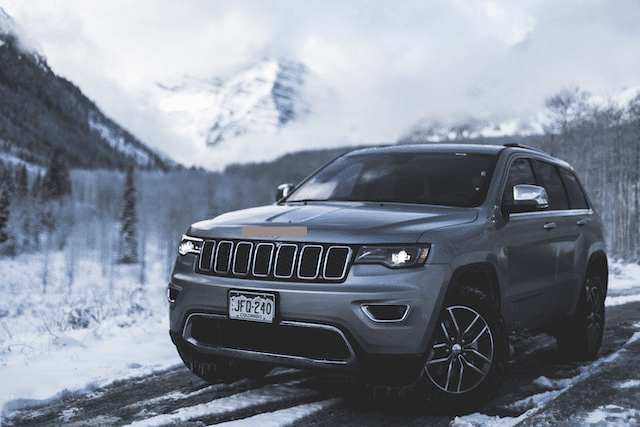 Featured image for "2014 Jeep* Grand Cherokee Oil Type" blog post. Gray Jeep driving through the mountains.