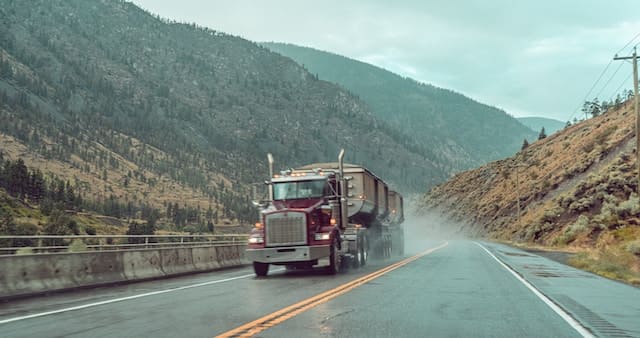 Featured image for "Best Gear Oil for Semi Trucks" blog post. Semi truck driving through the mountains.