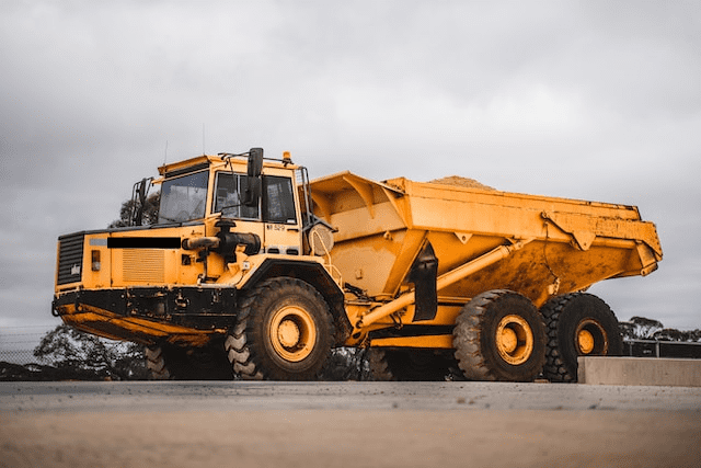 Featured image for "Best Hydraulic Oil for Dump Trucks" blog post. Yellow large dump truck.