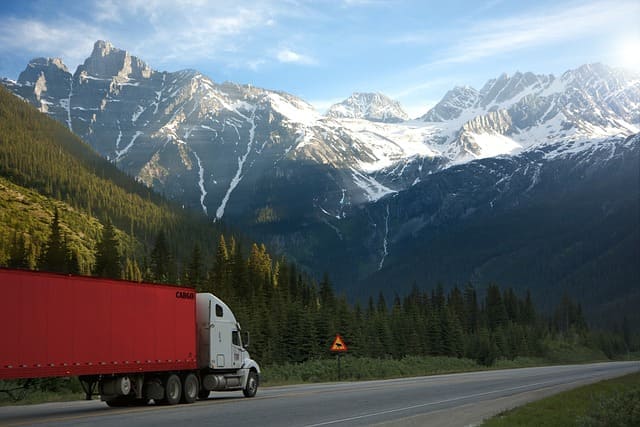 Featured image for "Fuel Efficiency Showdown: Unlocking the Mack* Anthem* vs Volvo* VNL* Smackdown" blog post. Truck driving through mountains.
